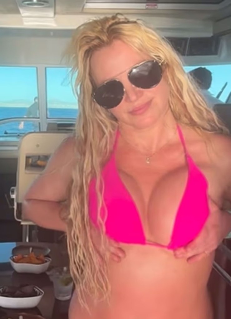 Britney Spears in a hot pink bikini and sunglasses on a boat.