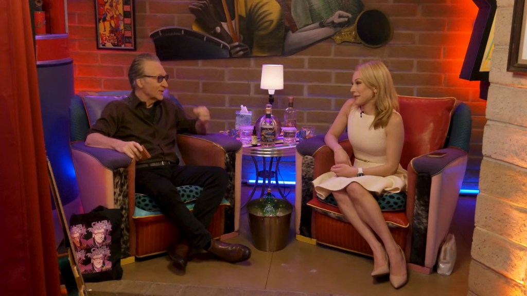 Maher and Kasparian sitting in chairs on a podcast set.