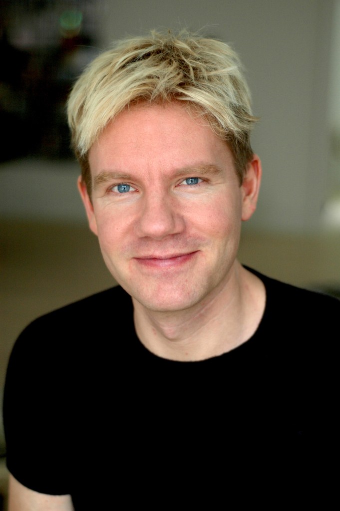 Headshot of Bjorn Lomborg, a man with blonde hair and blue eyes, smiling.