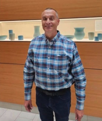 Dr. Randall Beallis wearing a blue plaid shirt and jeans.
