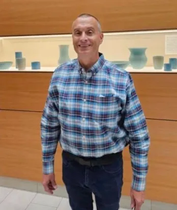 Dr. Randall Beallis wearing a blue plaid shirt and jeans.