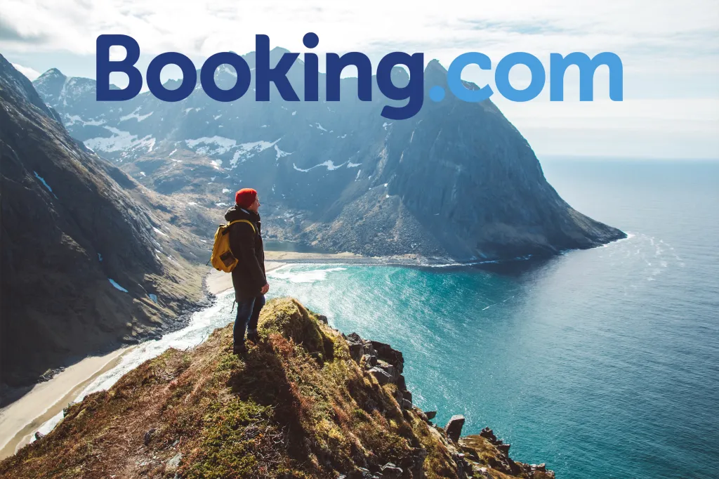 Booking.com logo over a person looking at the ocean and mountains.