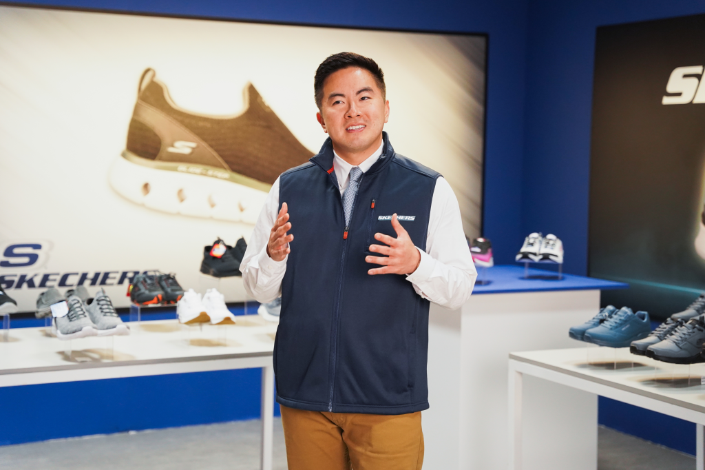 Bowen Yang presenting Skechers shoes in a commercial sketch.