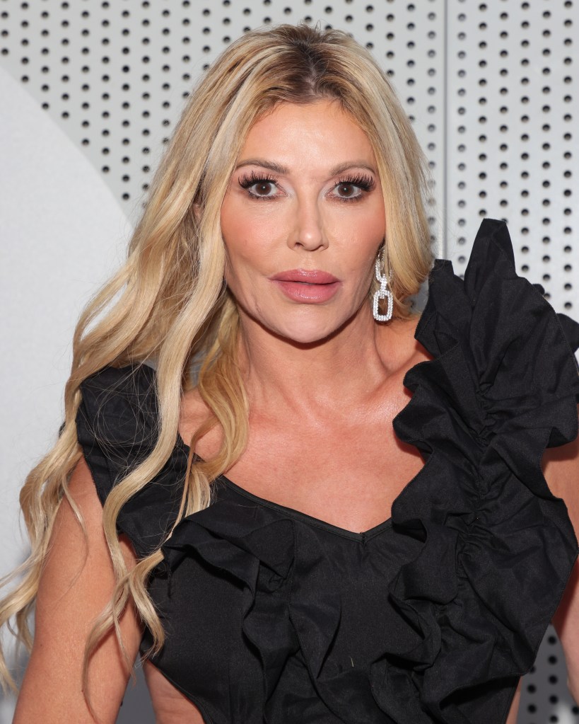 Brandi Glanville wearing a black ruffled top and large diamond earrings.