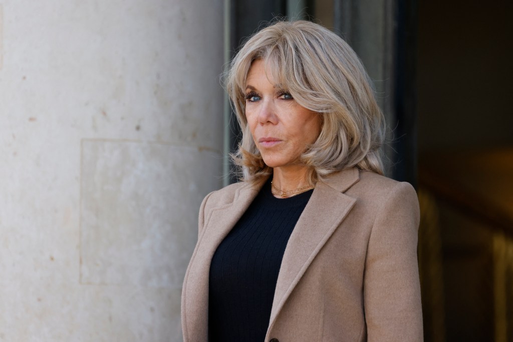 Brigitte Macron, wife of France's President, in a camel coat and black top.