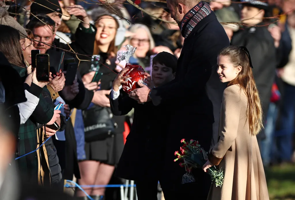 Prince Louis receiving a giant chocolate from a well-wisher while with Prince William and Princess Charlotte.