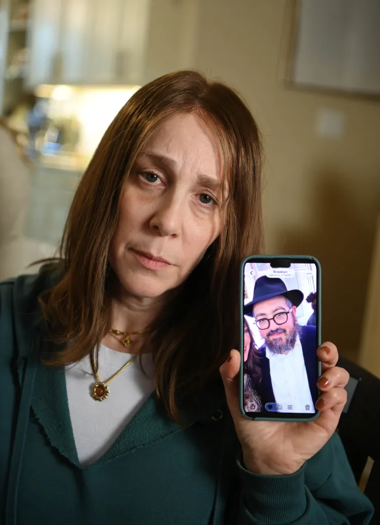 Chani Schlanger Drizin holds a photo of her deceased brother while sitting shiva at her Crown Heights home. She recounted the horror of losing her brother Rabbi Eli Schlanger during an antisemitic terrorist attack at a public Hanukkah celebration on Bondi Beach, Sydney, Australia. Photo by Helayne Seidman