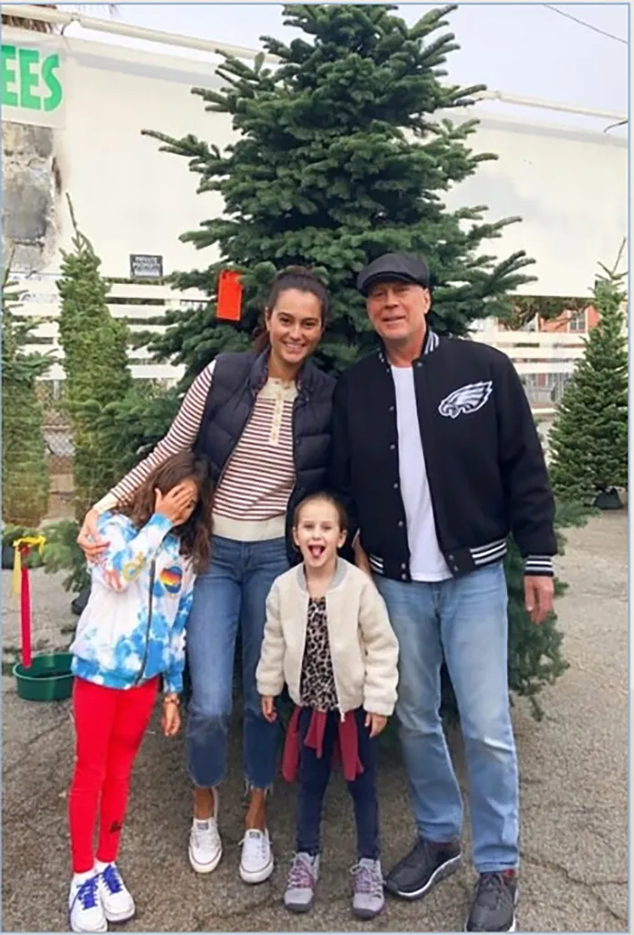 Bruce Willis and Emma Heming with their two daughters, Mabel and Evelyn, in front of a Christmas tree.