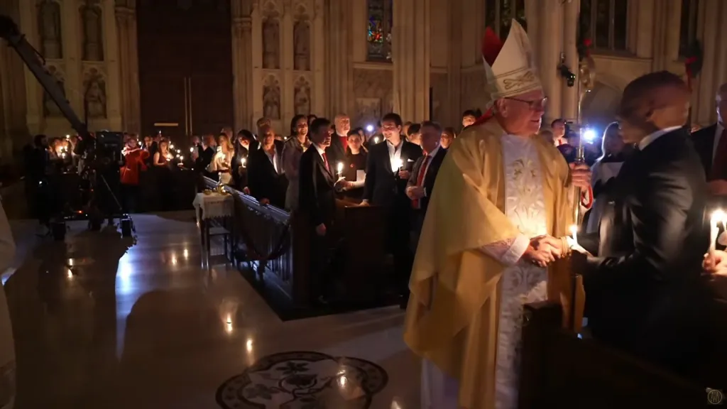 Cardinal Timothy Dolan shaking hands with a man during the final midnight mass at St. Patrick's Cathedral.