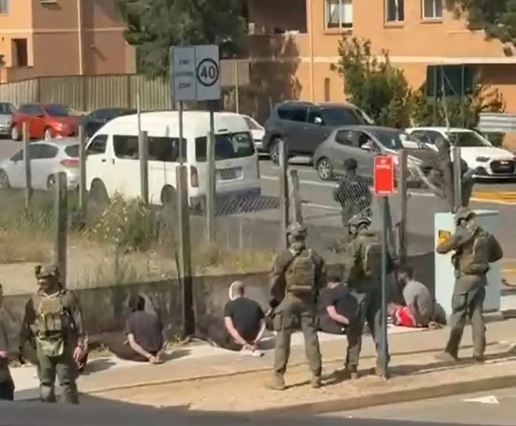 Heavily armed tactical police stop a carload of men and detain them on the ground.