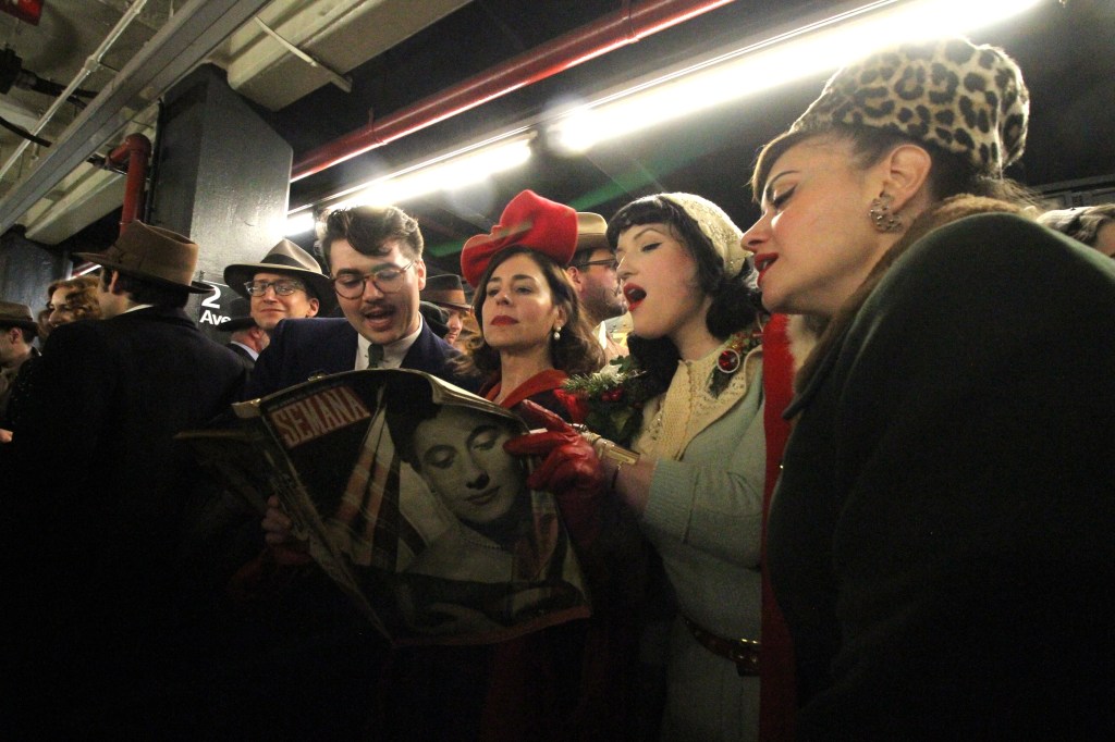 People dressed in 1930s-style clothing on a vintage train ride, one holding a 