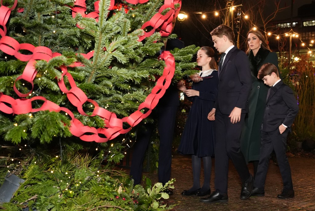 Catherine, Princess of Wales, and her children Prince George, Princess Charlotte, and Prince Louis decorating a Christmas tree.