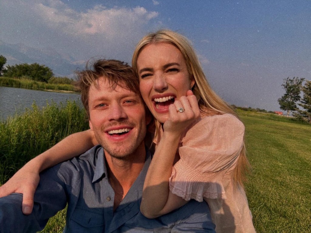 Emma Roberts showing her engagement ring while posing with her fiancé Cody John.