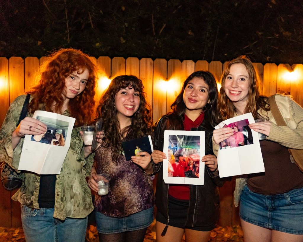 Four women holding up printed pictures of ex-partners.