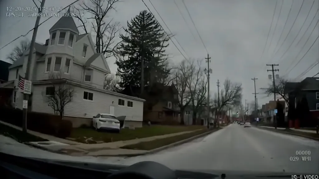 A white car crashed into the side of a white house.