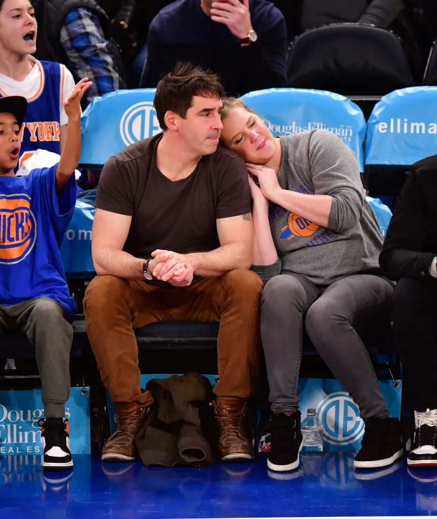 Amy Schumer resting her head on Chris Fischer's shoulder while watching a New York Knicks game.
