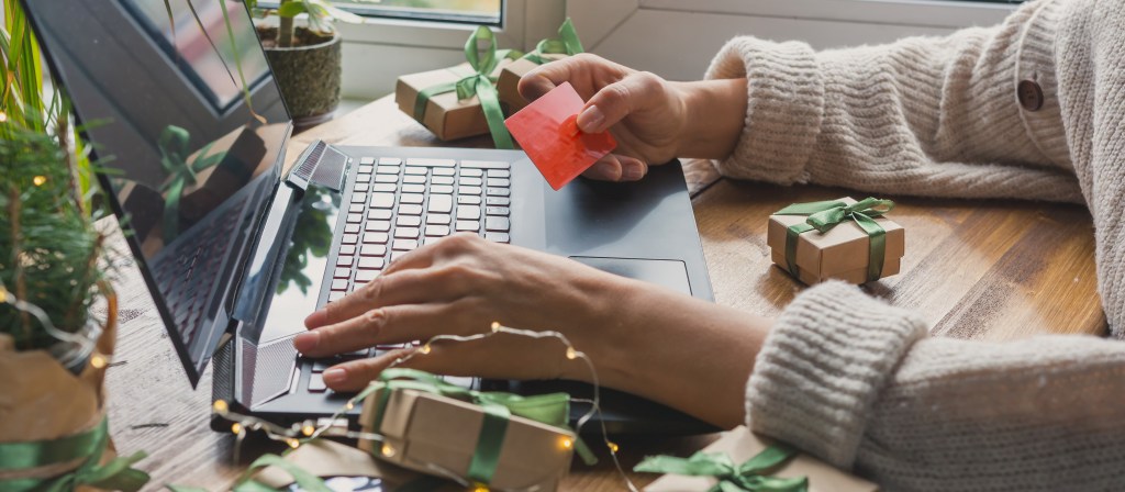 Person making a Christmas online purchase on a laptop with a credit card.