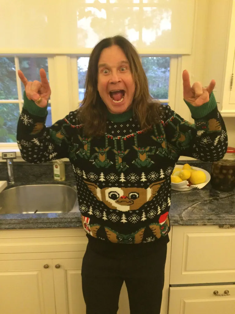 Ozzy Osbourne making rock-and-roll hand gestures while wearing a 