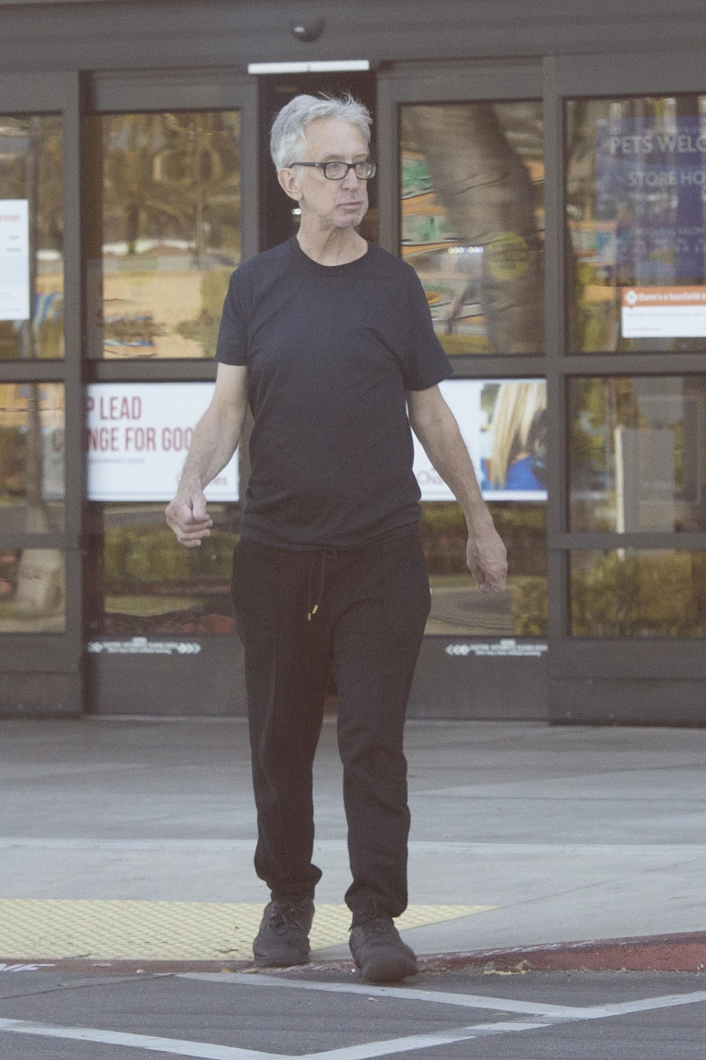 Andy Dick in a black t-shirt and pants in front of a store.