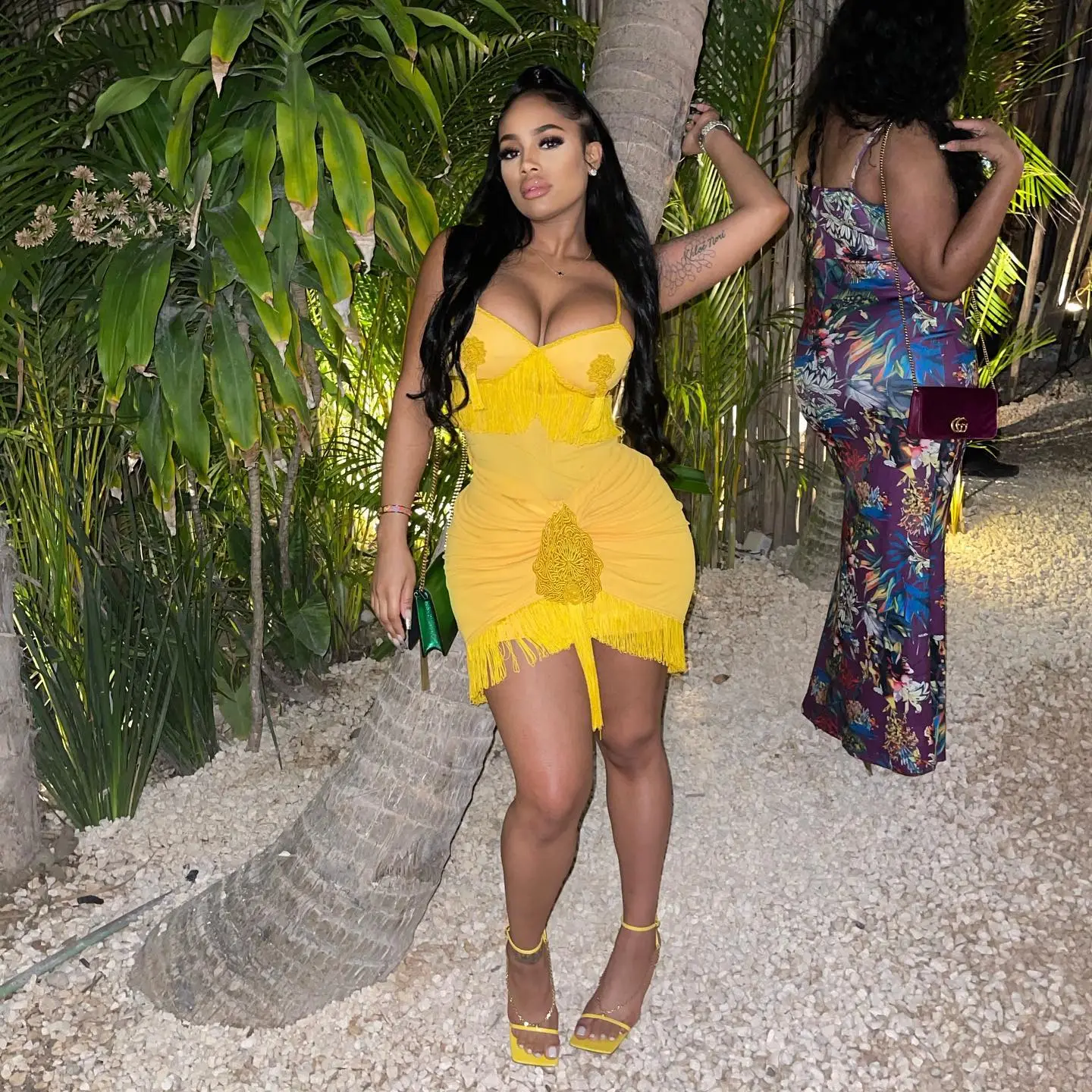 Joanna Donnejour in a yellow dress next to a palm tree.