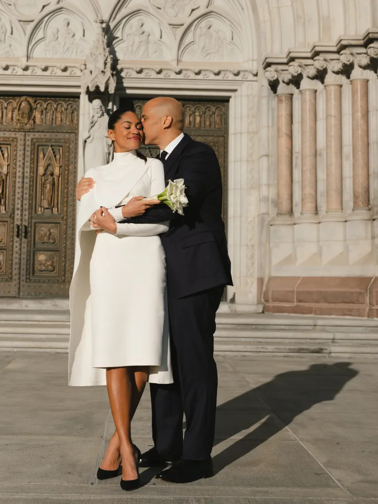 Cory Booker kissing Alexis Lewis on the cheek outside a courthouse.