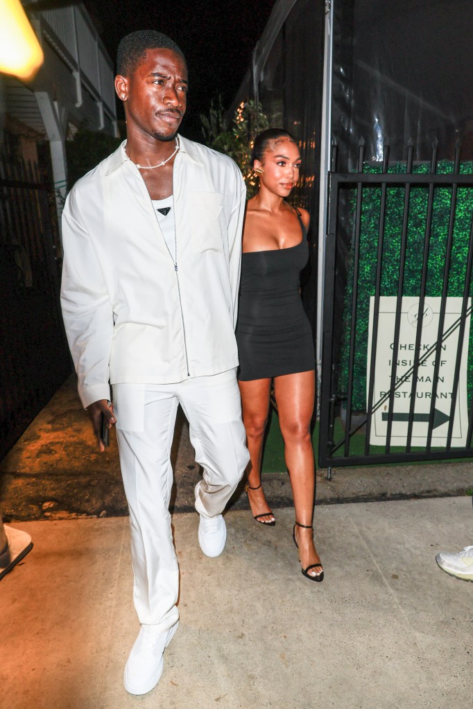 Damson Idris and Lori Harvey walking side by side, looking to the right.