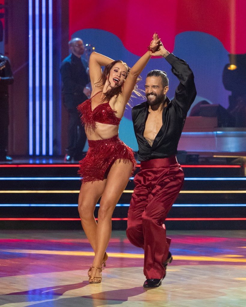 Whitney Leavitt and Mark Ballas dancing in red outfits on a stage.