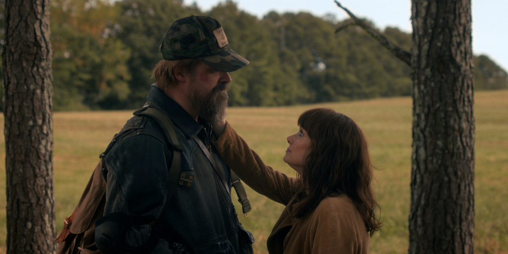 Jim Hopper looking at Joyce Byers who is touching his beard.