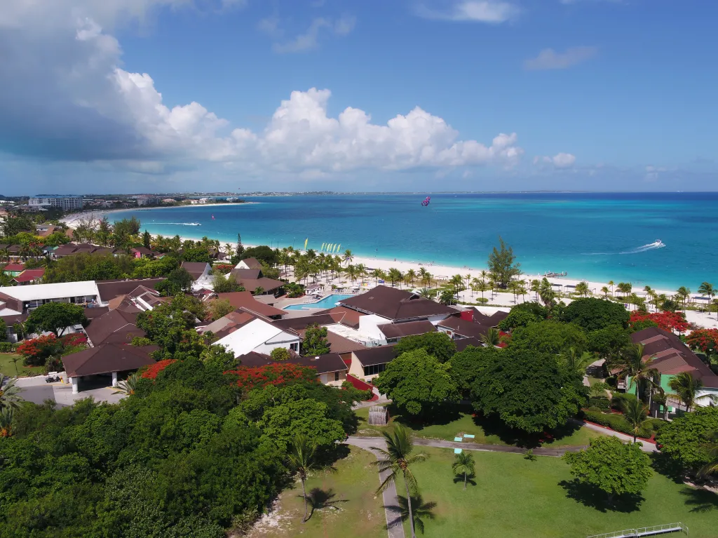 Drone view of the West Caicos bay, with a resort, beach, and turquoise ocean.