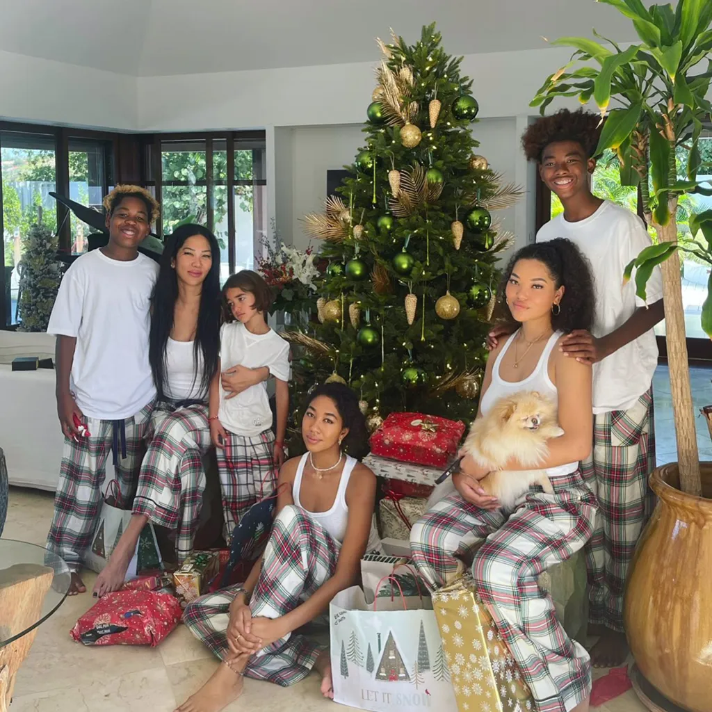 Kimora Lee Simmons with her five children and a dog, sitting around a Christmas tree with presents.