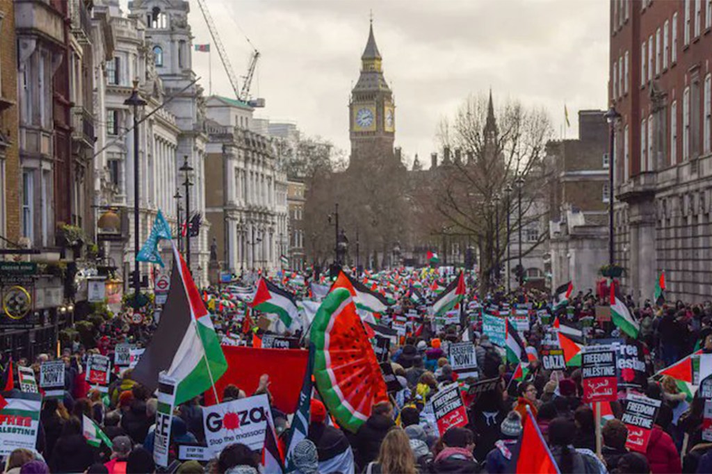 A large pro-Palestine demonstration with Palestinian flags and signs saying