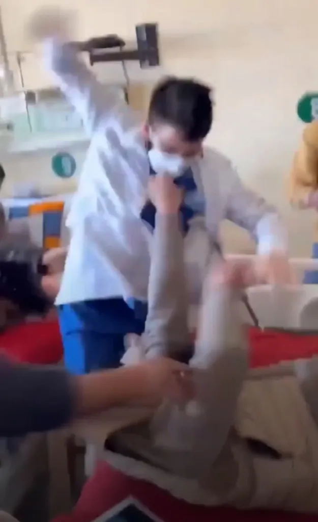 A doctor repeatedly punching a patient in a hospital room.