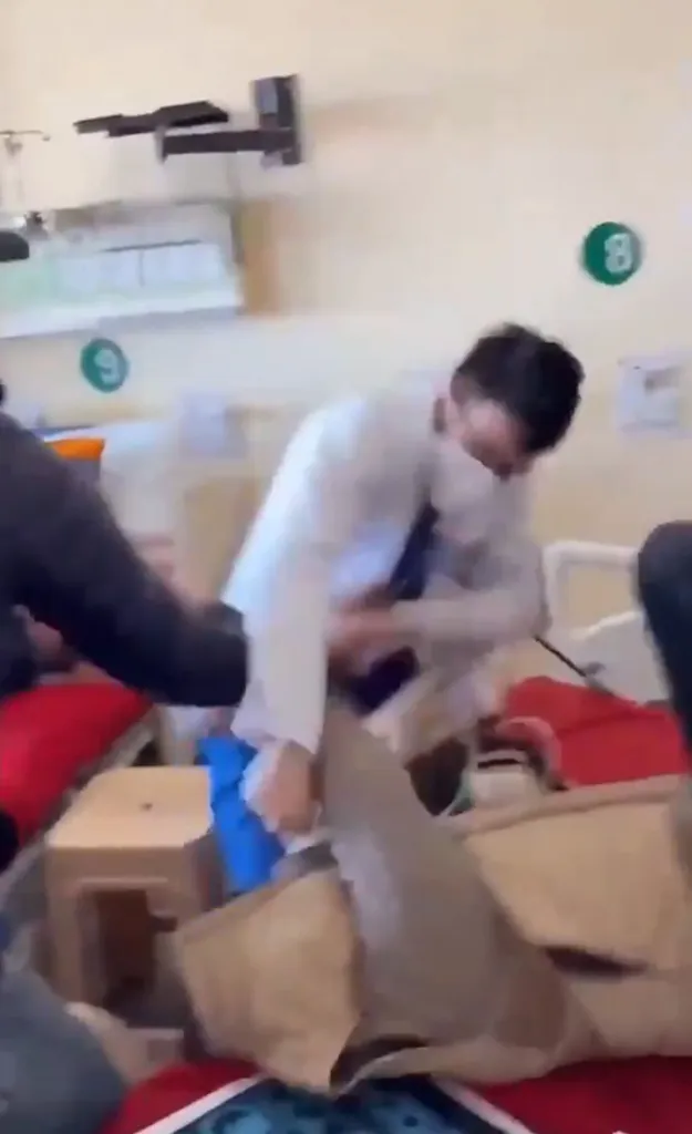 A doctor in a white coat punching a patient lying on a hospital bed.