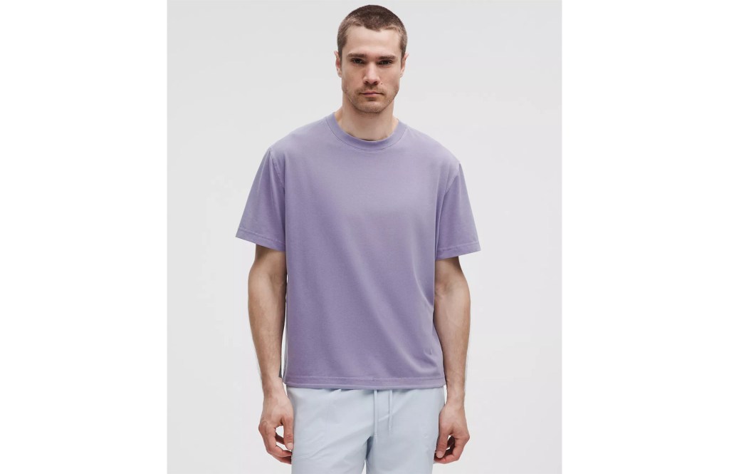 Man wearing a lavender t-shirt and light blue shorts.