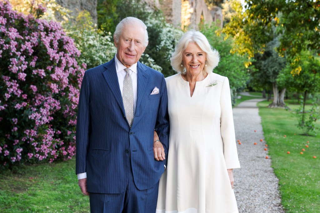 King Charles III and Queen Camilla pose for a portrait in a garden.