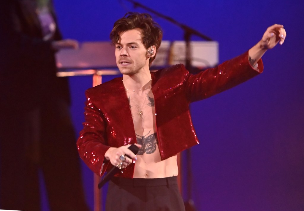 Harry Styles, in a sequined red jacket and black pants, performing on stage at The BRIT Awards 2023.