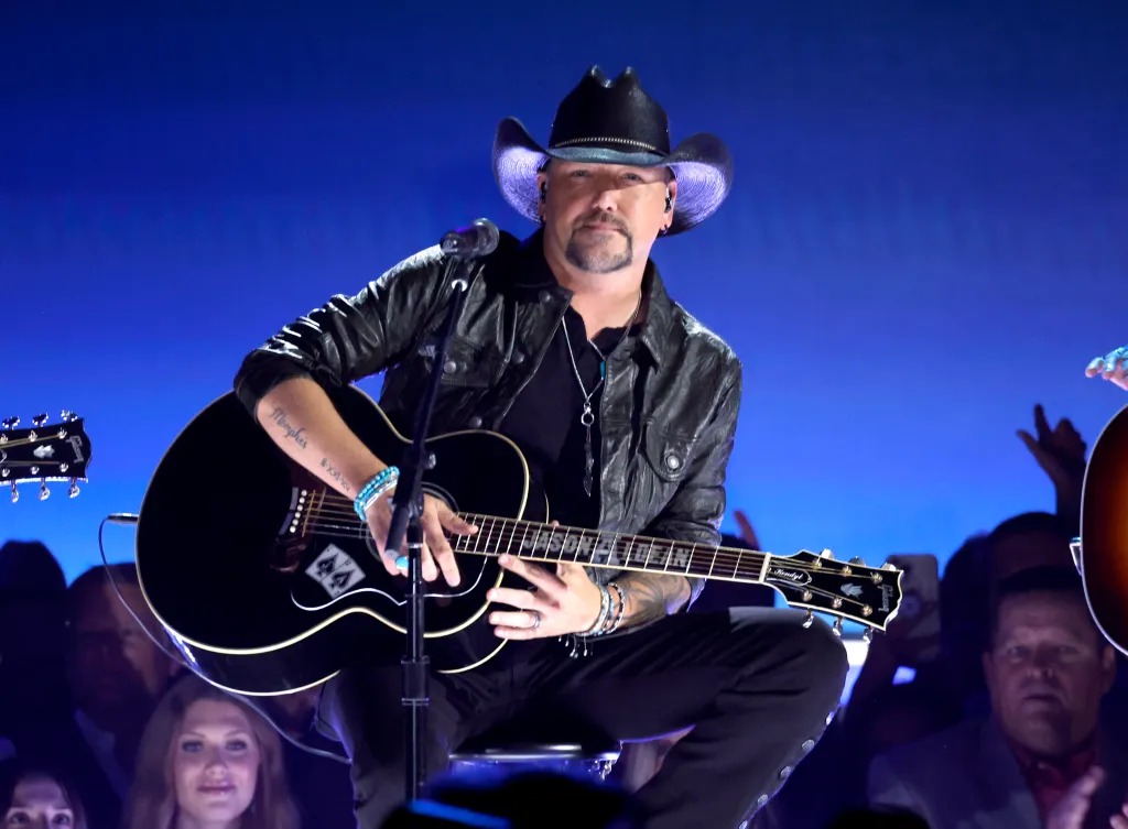 Jason Aldean performs with a black acoustic guitar.