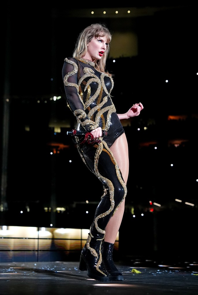 Taylor Swift performing in a black sequined bodysuit with gold snake-like embellishments.