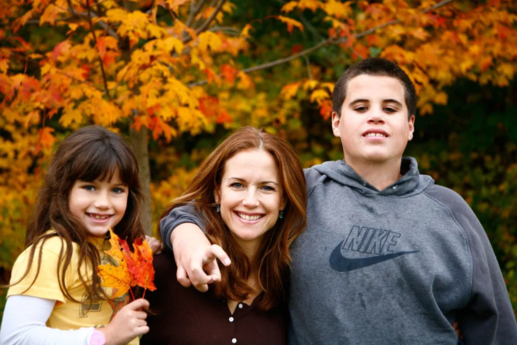 Kelly Preston with her children Jett and Ella against a backdrop of autumn leaves.