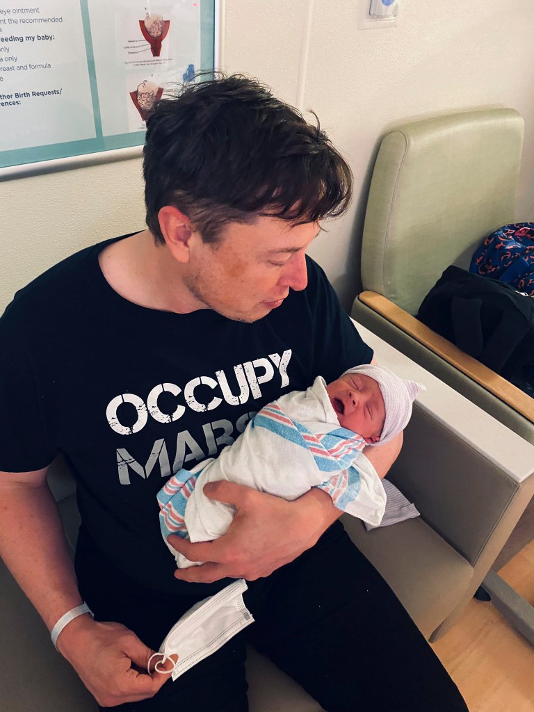 Elon Musk holding his newborn son, X Æ A-12, in a hospital room.