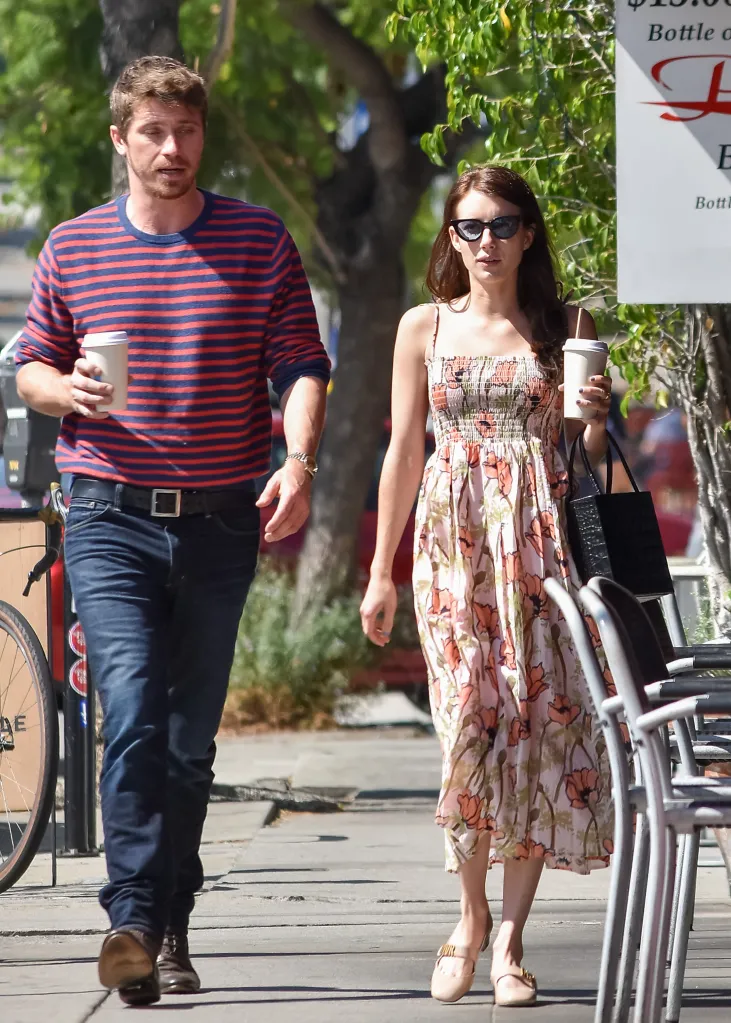 Emma Roberts in a sundress and Garrett Hedlund in a striped shirt holding coffee cups.