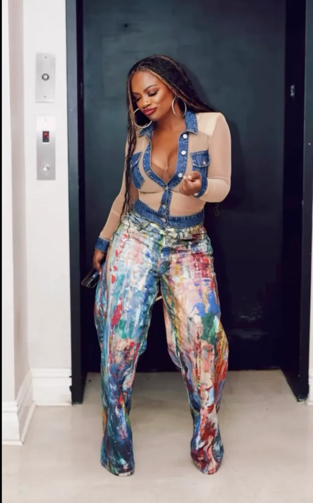 Kandi Burruss in a sheer top with denim accents and paint-splattered wide-leg pants.