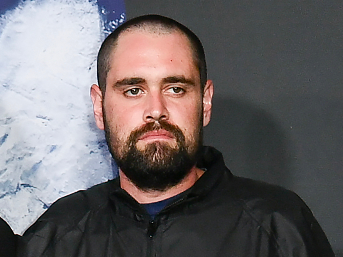 Nick Reiner, with a short haircut and beard, wearing a black jacket, arrives at the premiere of 