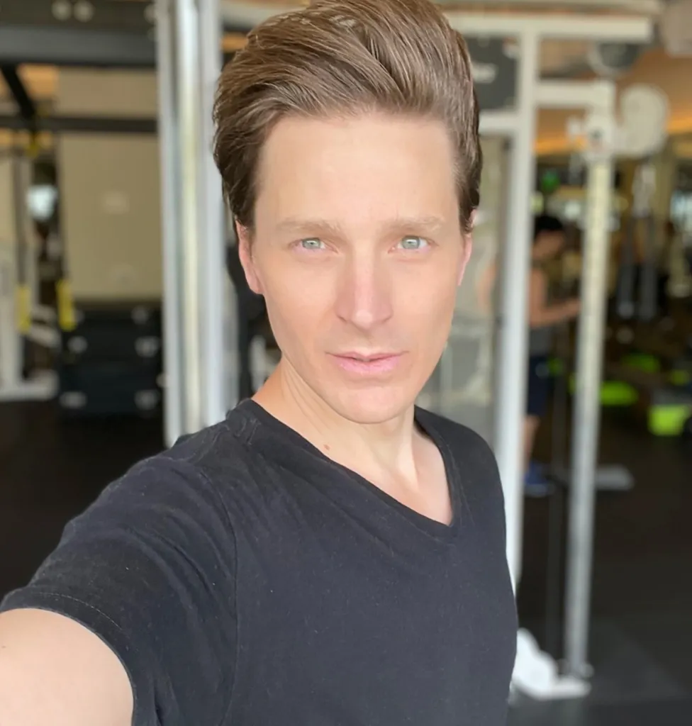 Ernest Heinz with short brown hair and light eyes, wearing a black t-shirt.