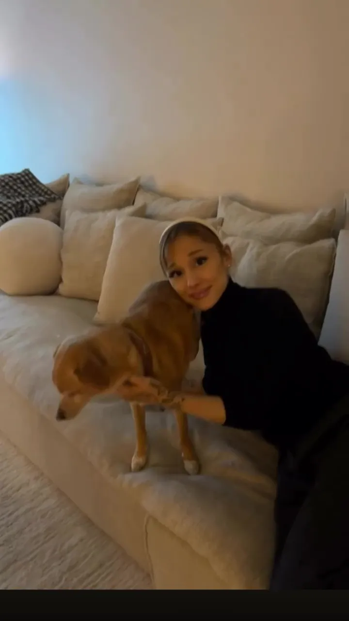 Ariana Grande sitting on a couch with her dog.