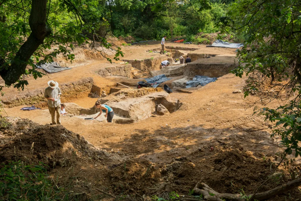 Archaeological excavation site at Barnham, Suffolk, England with several archaeologists working in trenches.