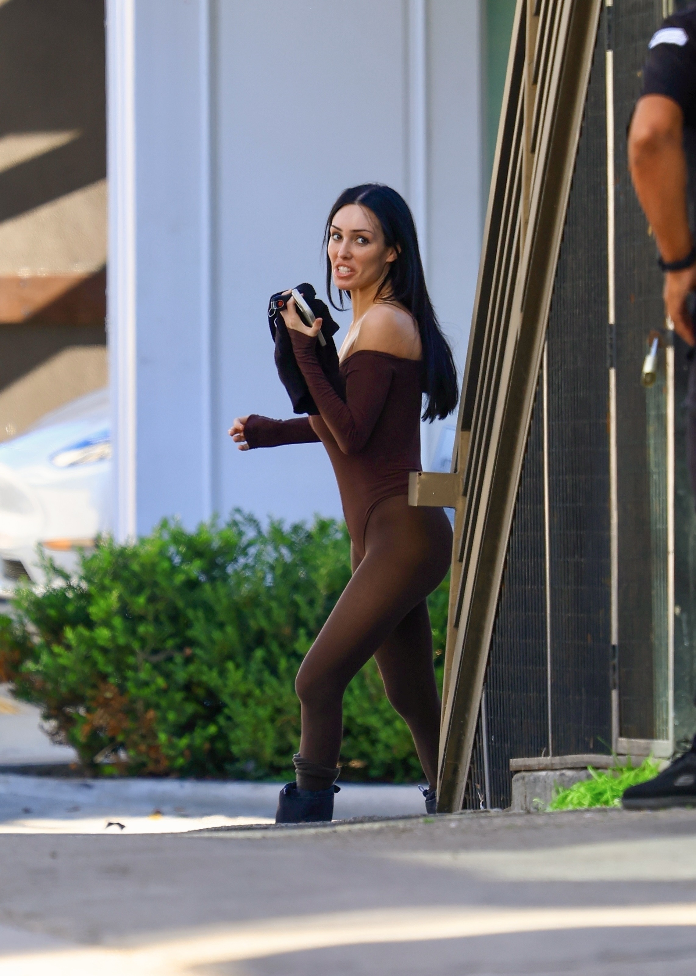 Bianca Censori in a brown bodysuit and moon boots holding a phone.