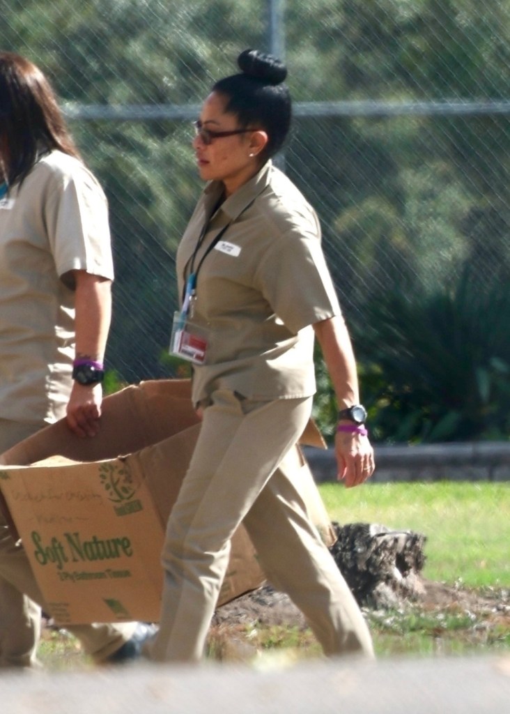 Jen Shah wearing a beige uniform and carrying a cardboard box labeled 