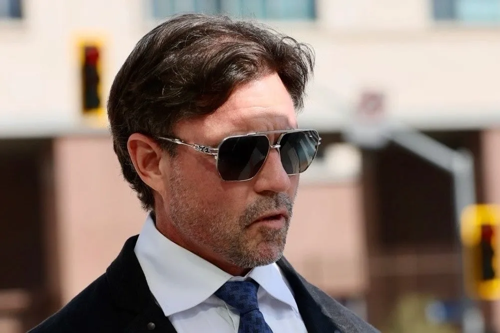 Aaron Phypers in sunglasses being interviewed by a reporter from Entertainment Tonight outside the courthouse.