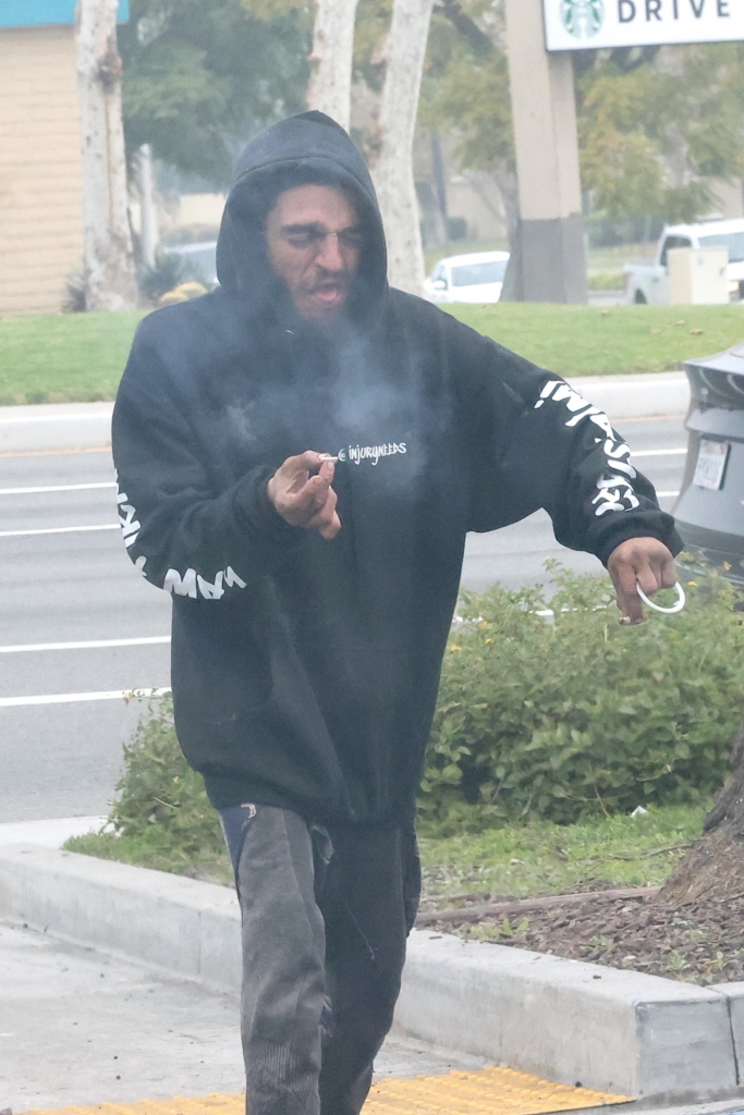 Tylor Chase smoking a cigarette while walking in a parking lot.